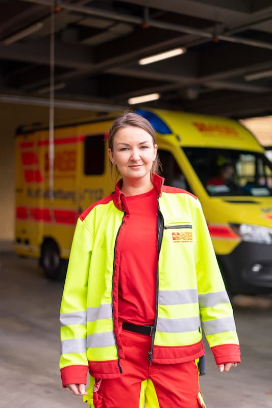 Trainee in der Notfallsanitäter-Ausbildung vor Rettungswagen