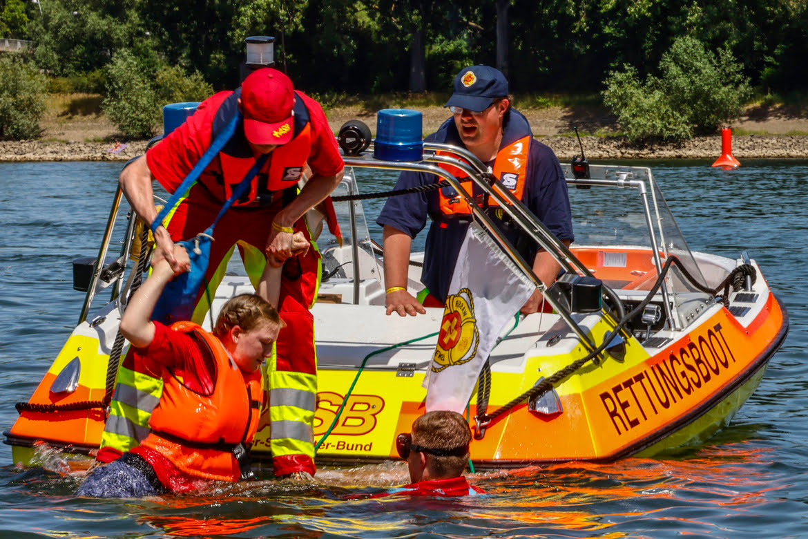 Die ASB Wasserrettung hilft und hebt ein Mädchen aus dem Wasser auf das sichere Rettungsboot